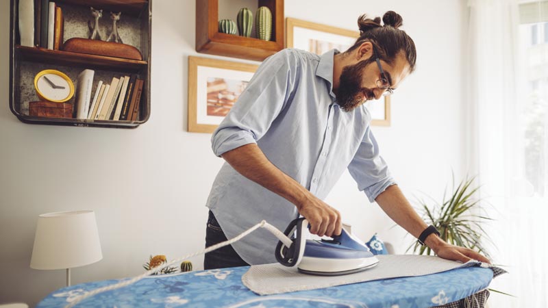 homem a passar a ferro em casa